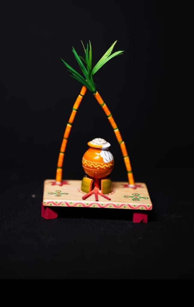 Here are some title suggestions:1. Wooden Pongal Pot Stand 2. Traditional Pongal Decoration3. Handmade Pongal Festival Decor4. South Indian Pongal Festival Decoration5. Pongal Pot Stand view 2